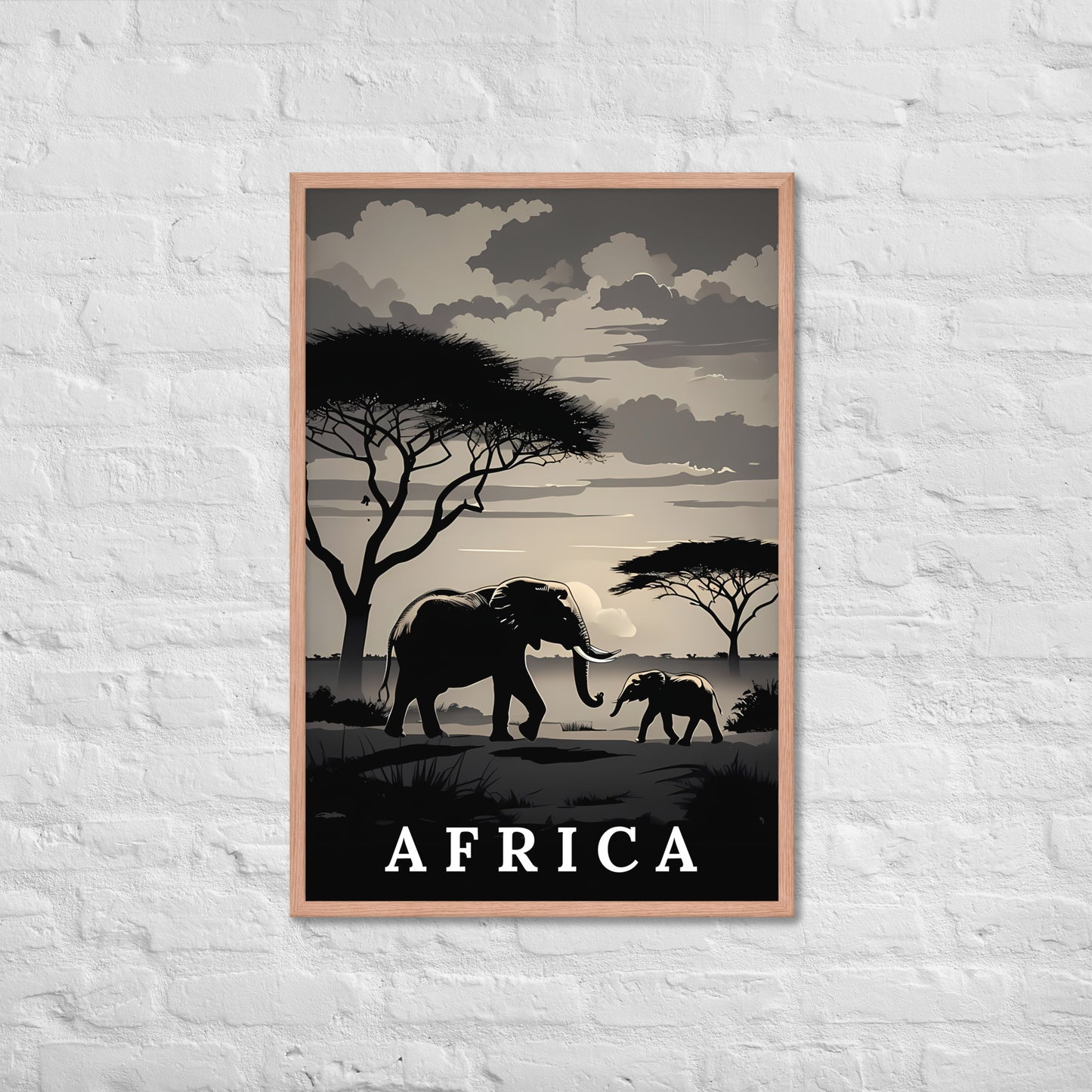 A framed travel-style poster featuring silhouetted elephants, trees, and a cloudy sky with the word "AFRICA" at the bottom, displayed against a white brick wall.