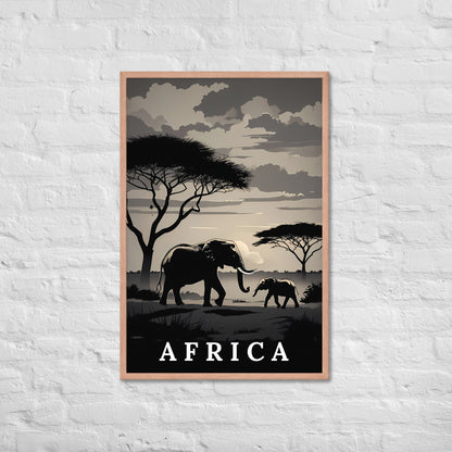 A framed travel-style poster featuring silhouetted elephants, trees, and a cloudy sky with the word "AFRICA" at the bottom, displayed against a white brick wall.
